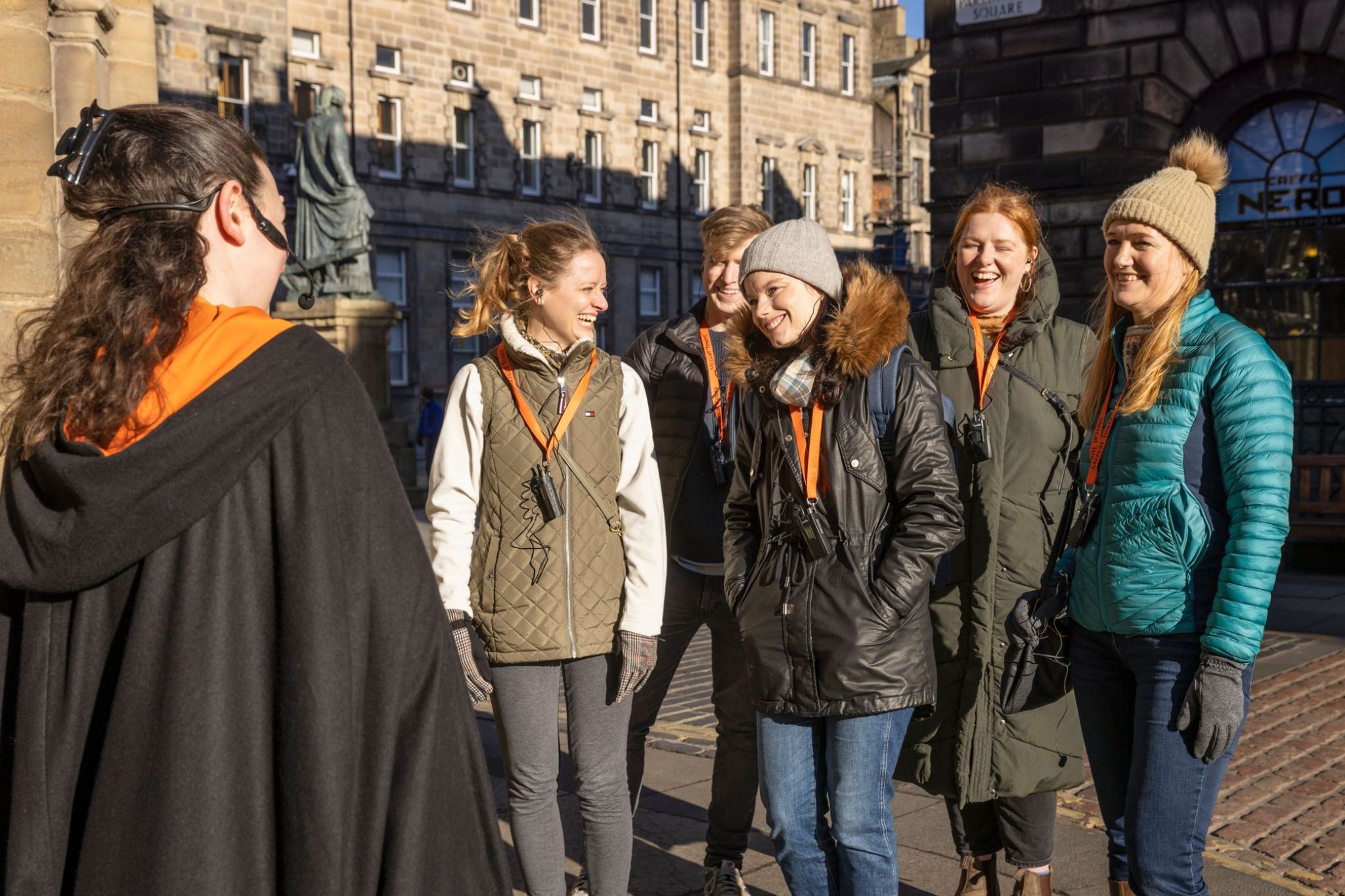 A Mercat Tours guide welcomes a group at The Mercat Cross on the Royal Mile, Edinburgh